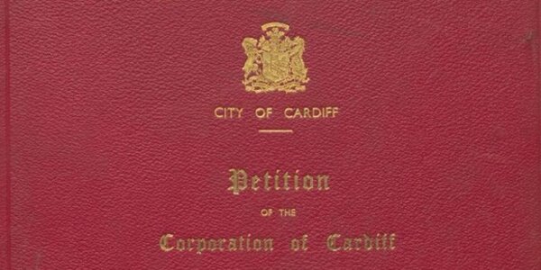 Close up of a red book cover with gold lettering reading 'City of Cardiff: Petition of the Corporation of Cardiff'