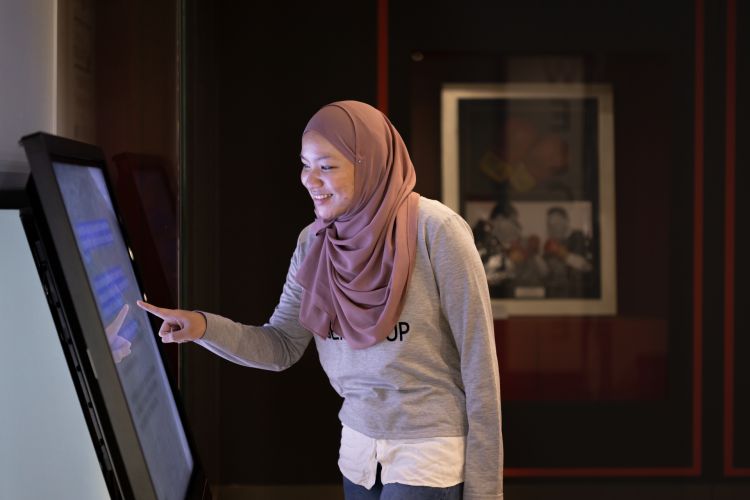 A visitor interacting with a touchscreen in an exhibition at the Library